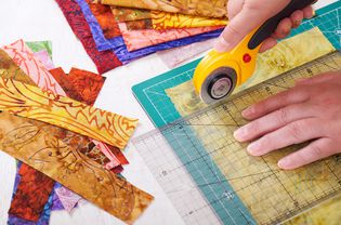 Process cutting fabric pieces by rotary cutter on mat using ruler