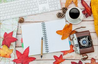 A desk with various fall leaves along with office supplies