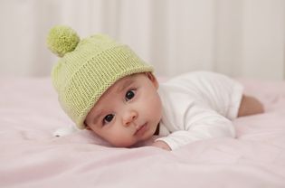 男婴戴着羊毛帽躺在床上，肖像