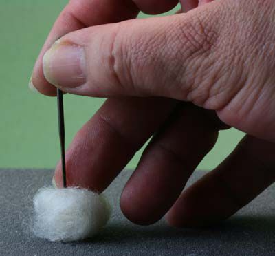 一只手一个制毡针通过一个小的纤维球垫起来。