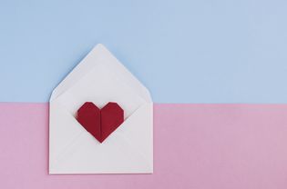 情人节信:信封与折纸心形准备爱的信息在柔和的彩色背景。正上方和复制空间