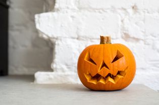 Halloween Pumpkin Lantern in front of a white brick wall