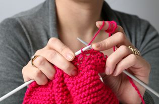 Woman knitting a pink scarf
