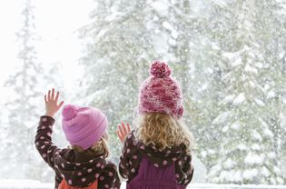 Young sisters look at snowfall outside