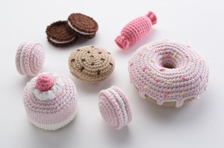 Crocheted stuffed dessert items such as a donut, macarons, cookies and other treats