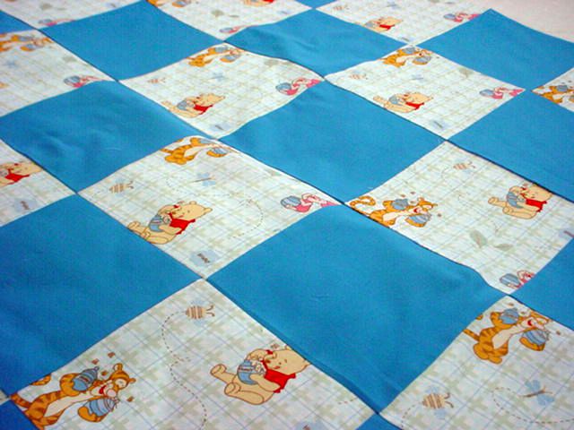 婴儿被子用蓝色方块和小熊维尼广场。