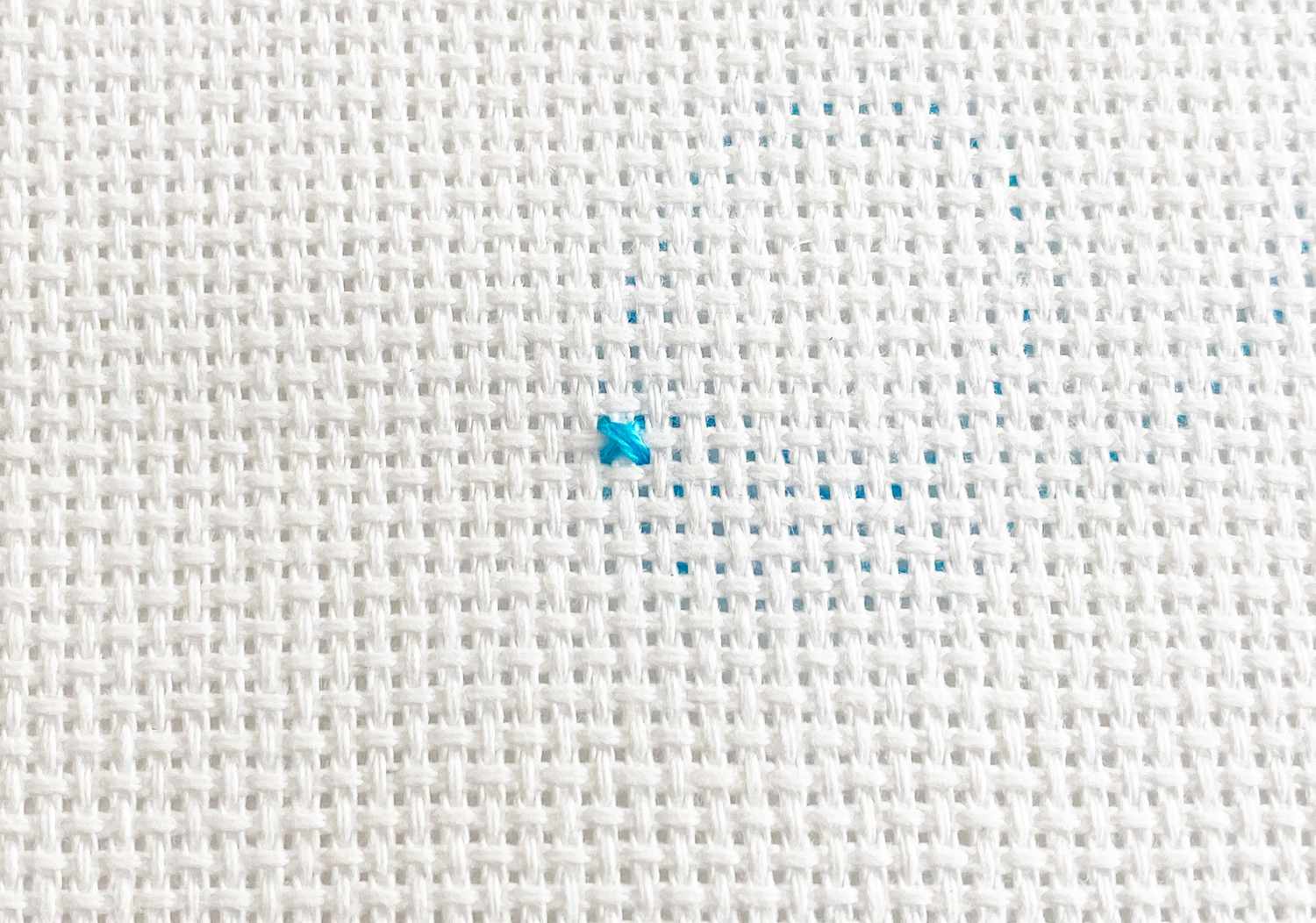 A close-up of a blue cross stitch