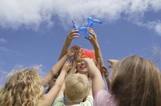 Children reaching for balloon sculpture
