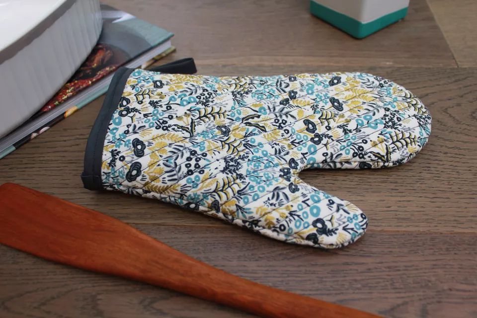 A floral oven mitt laying on a table