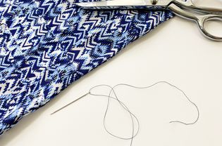 A blue blouse, scissors, and a threaded needle