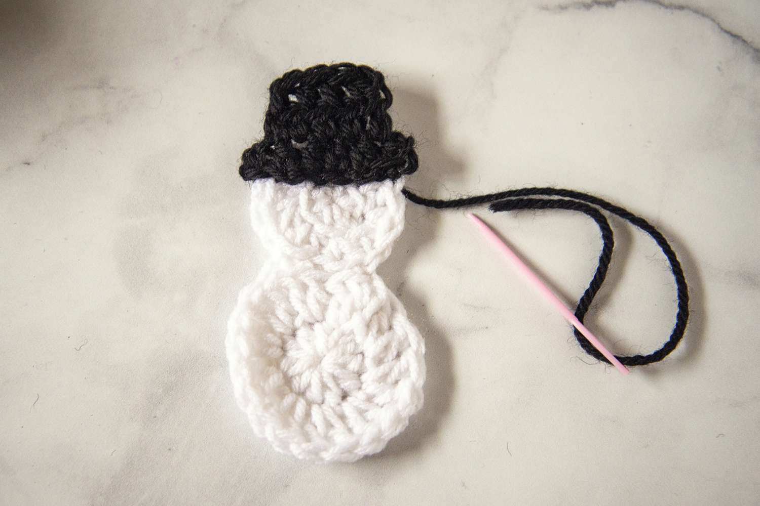 A crocheted snowman with black hat.