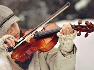 女子戴着无指手套拉小提琴。