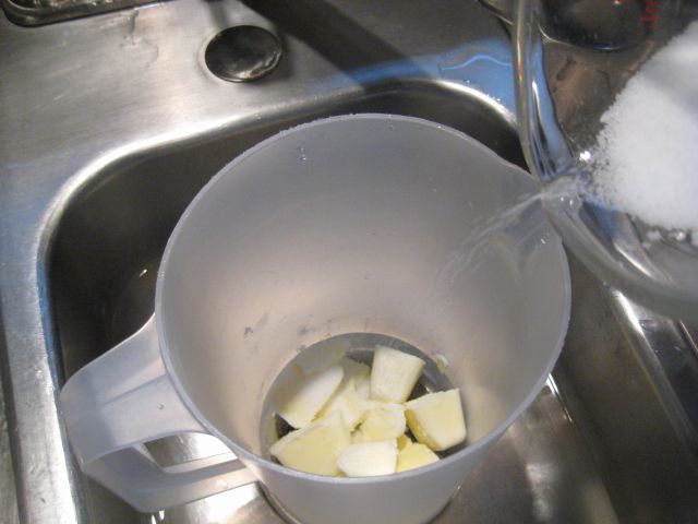 Adding lye to cream cubes in pitcher in sink
