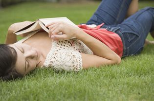 一个女人拿着一本书躺在草地上
