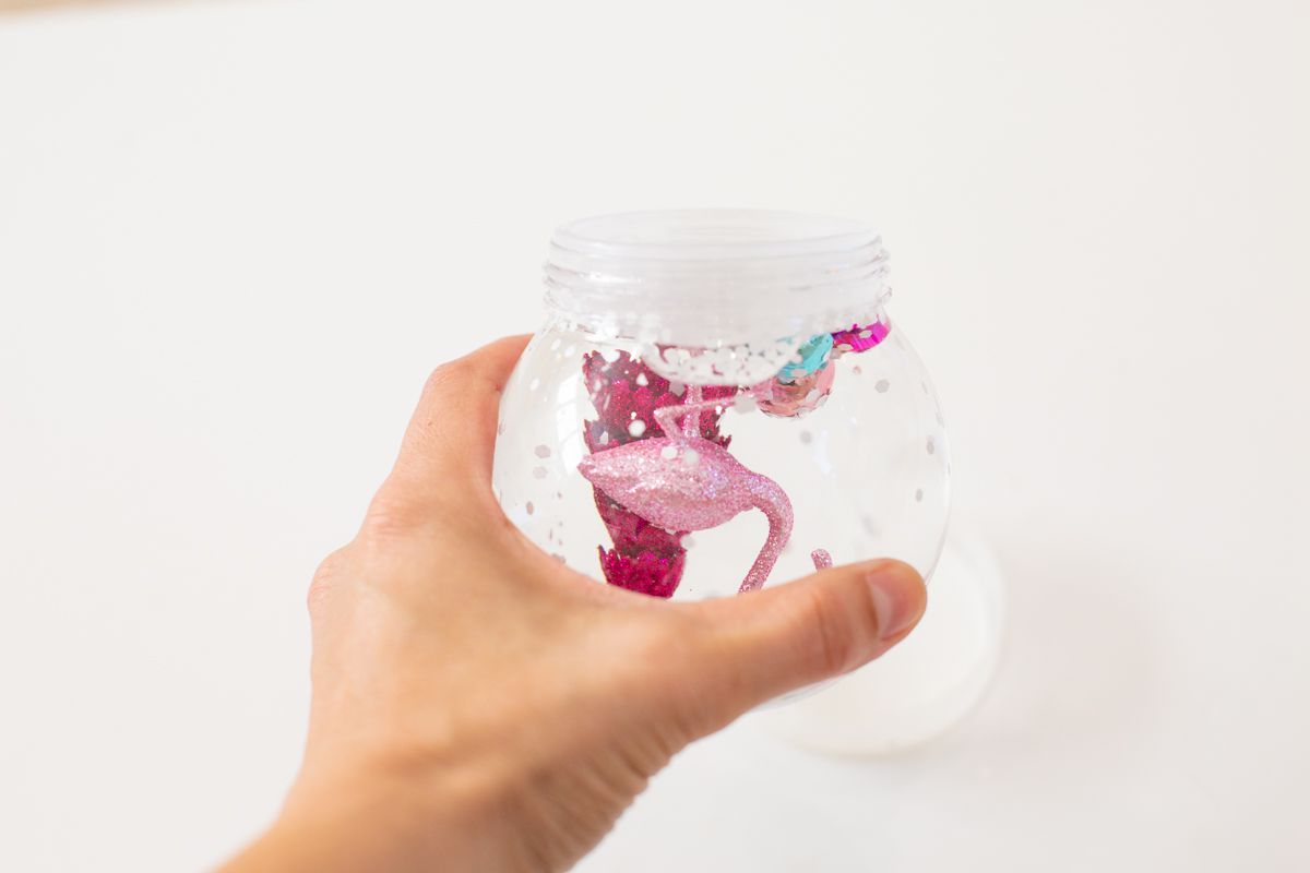 A hand holding the final DIY snow globe upside down