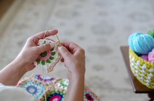 这个女人正在用彩色的纱线钩针编织。