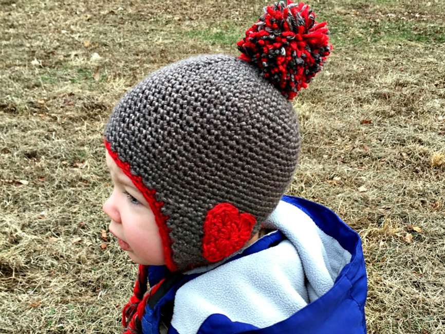 孩子穿一件黑色和红色crocet与心脏贴花的耳朵。