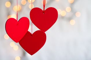 Three hanging red hearts on defocused light background