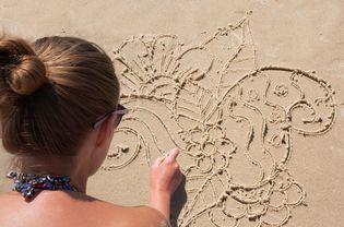 小女孩在沙滩上涂鸦。