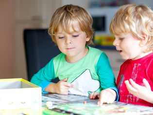 Two blond boys playing a board game at home.