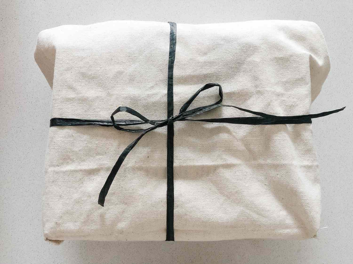一个用白色可重复使用的袋子包装的礼物，用黑色的丝带系上。