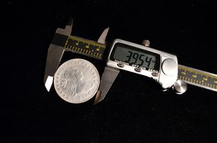 一枚假币正在用高精度数字卡尺测量。