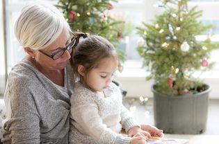 Grandmother Watching Granddaughter Drawing in Front of Christmas Trees