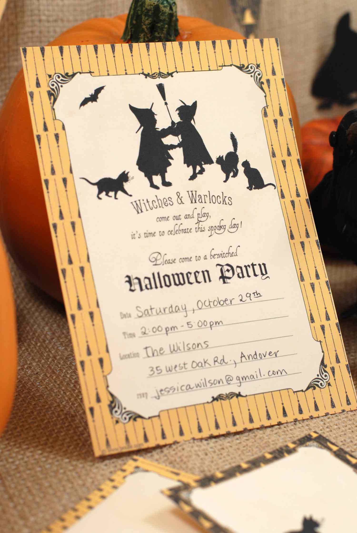 A Halloween Party Invitation Leaning Against a Pumpkin