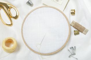 特写的木制绣花框架，剪刀，线，顶针，针，和干净的白色织物刺绣。为爱好设计留出空间