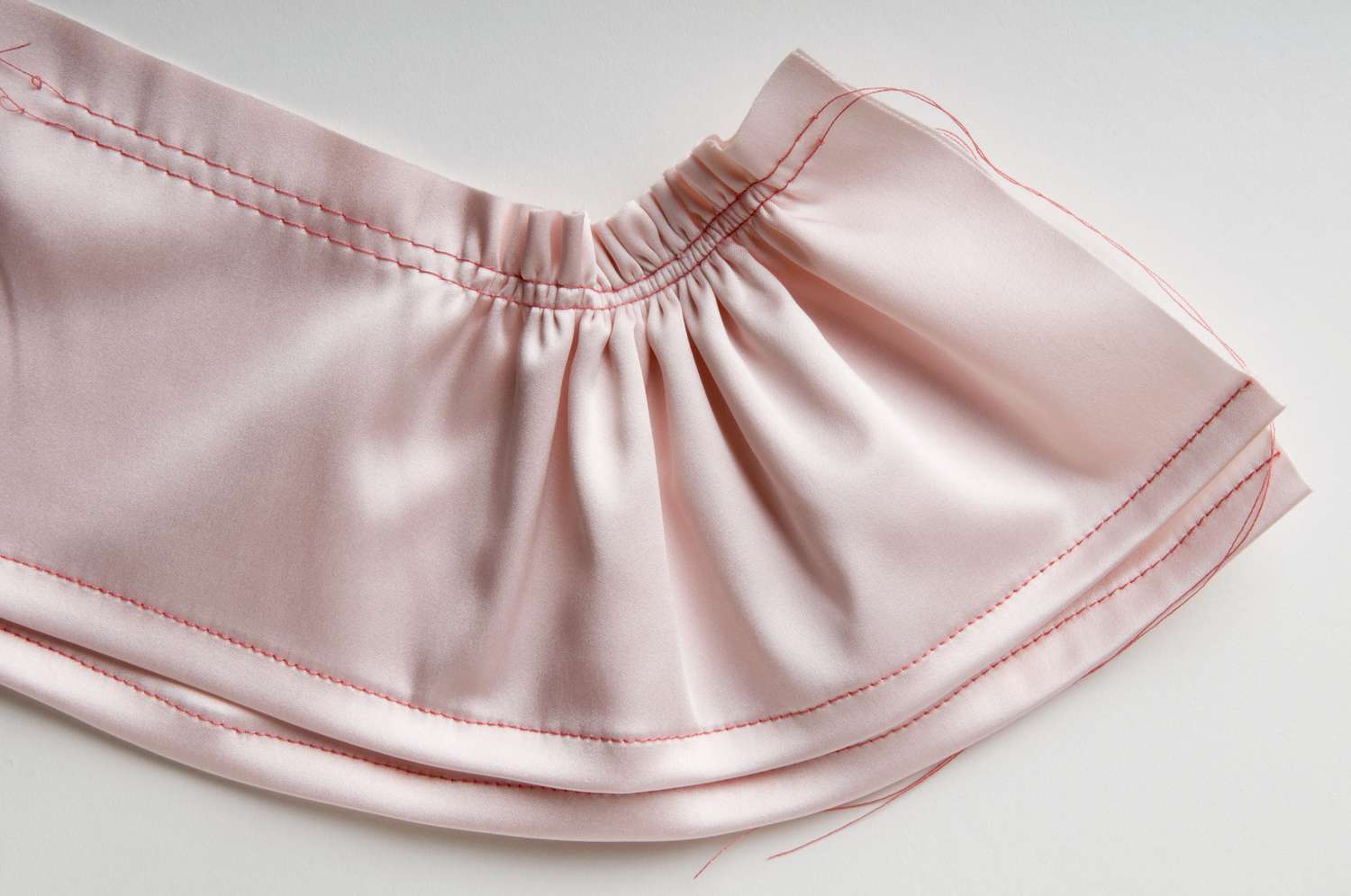 粉红色织物的双褶边，上边缘有两排聚针，下边缘有单排聚针