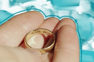 hand holding gold wedding band with engraving on the inside