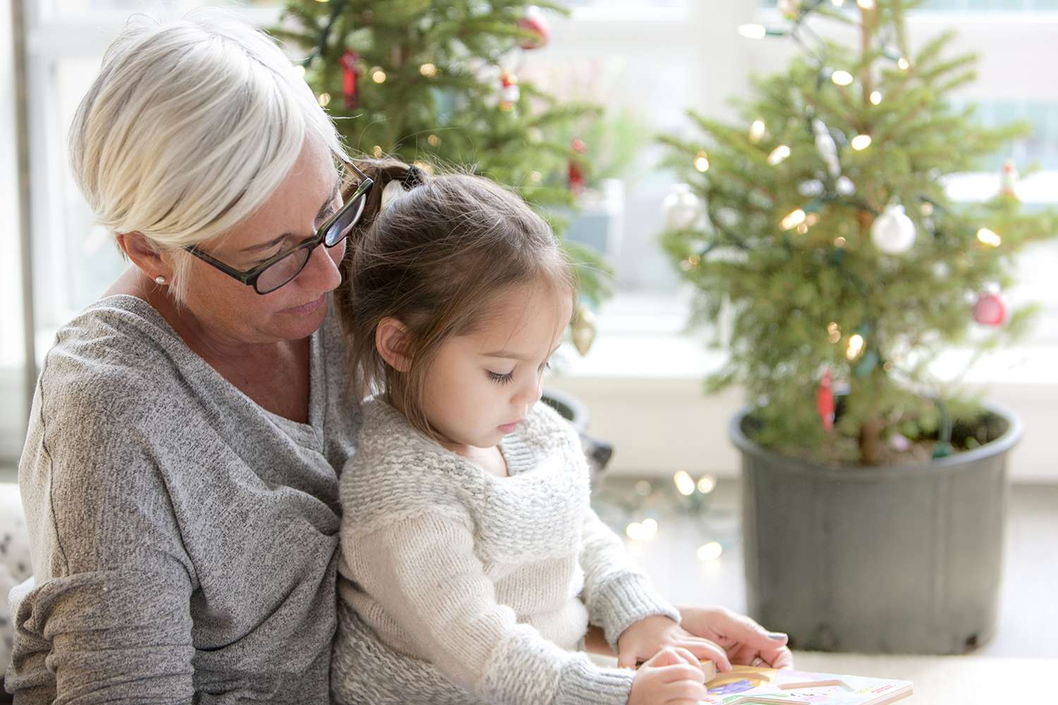 奶奶看着孙女在圣诞树前画画