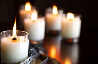 Five paraffin wax candles lit on a table.