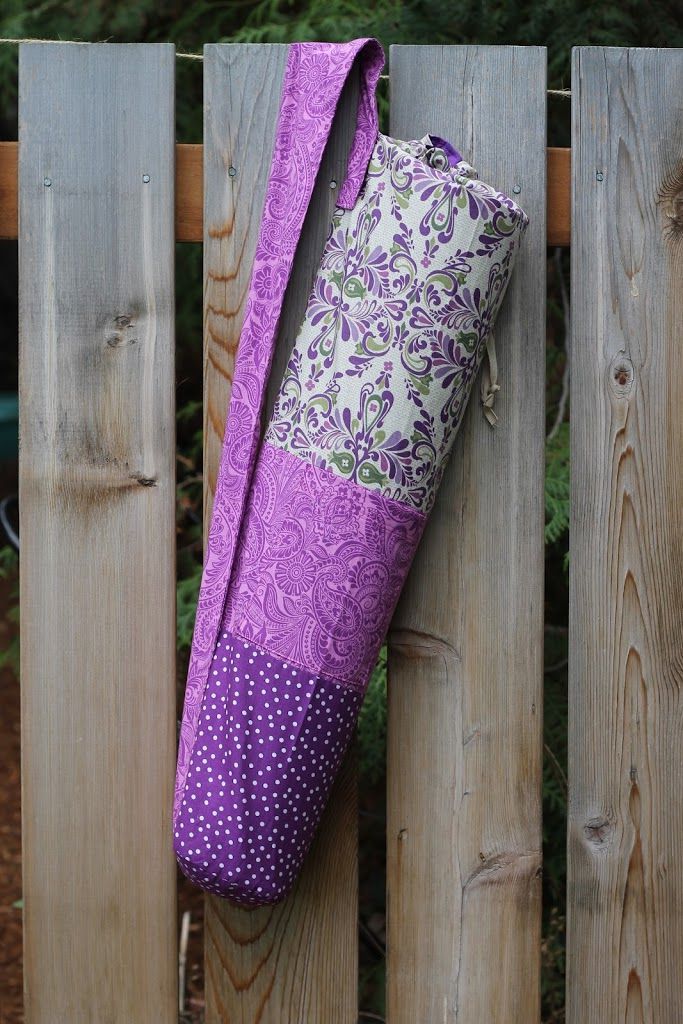 一个紫色的瑜伽垫袋挂在木栅栏上