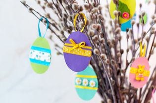 复活节彩蛋课以颜色纸用丝带装饰和按钮在柳树的树枝