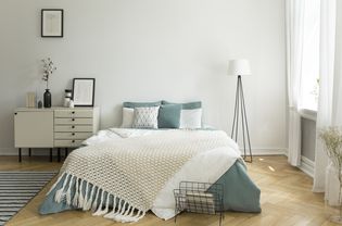 一个舒适的床上,浅灰绿色和白色亚麻,枕头和毯子在一个女人的明亮的卧室室内与windows。真实的照片。