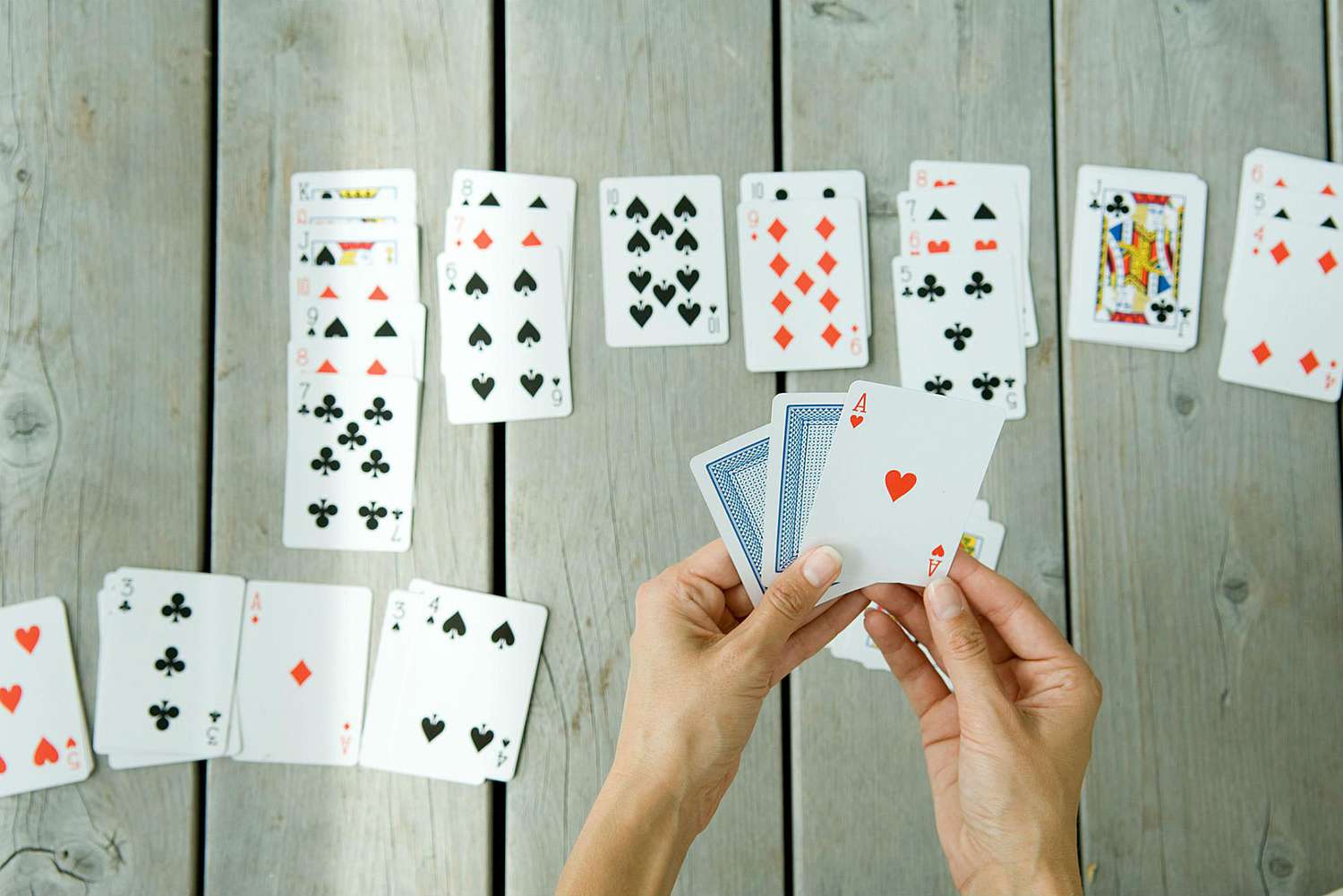 玩单人纸牌的女人，手牌和纸牌的裁剪视图