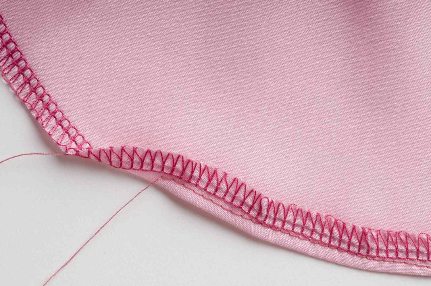 粉红色织物弯曲边的包缝和直缝