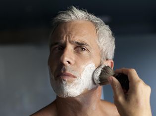 成熟男人在刮胡子前在脸上涂泡沫