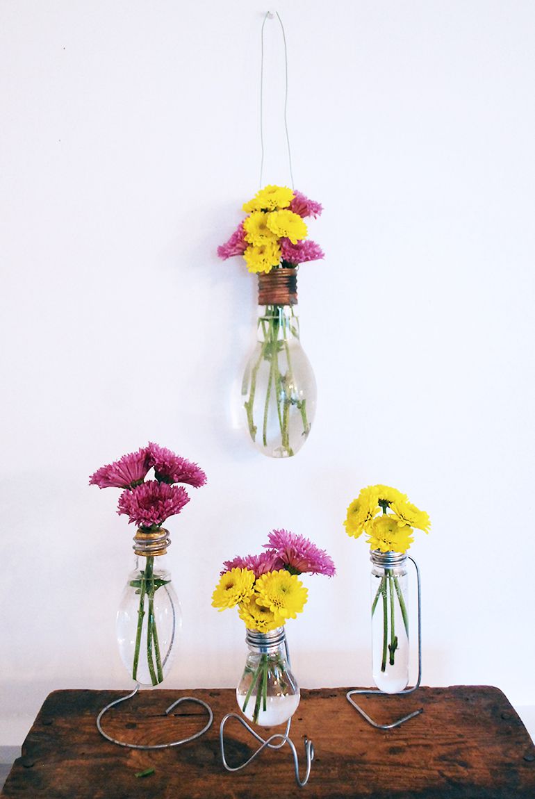 花瓶由灯泡挂用鲜花,站在桌子上。