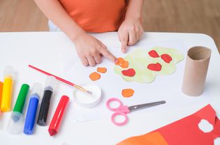 俯视图小3岁的学步男孩喜欢用胶水在家里做艺术，有趣的纸和胶水工艺品的幼儿，儿童艺术项目