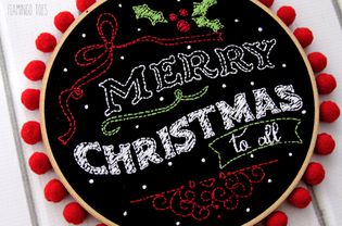 圣诞快乐粉笔艺术刺绣图案黑色织物和放置在一个刺绣箍。