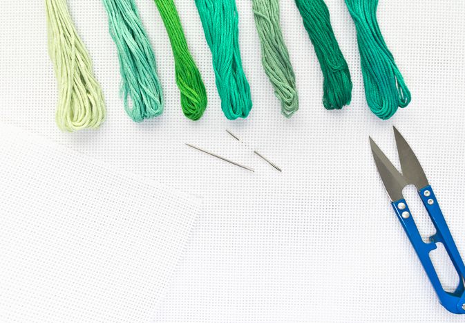 平躺一个刺绣顶视图画布,针,线程在绿色的颜色