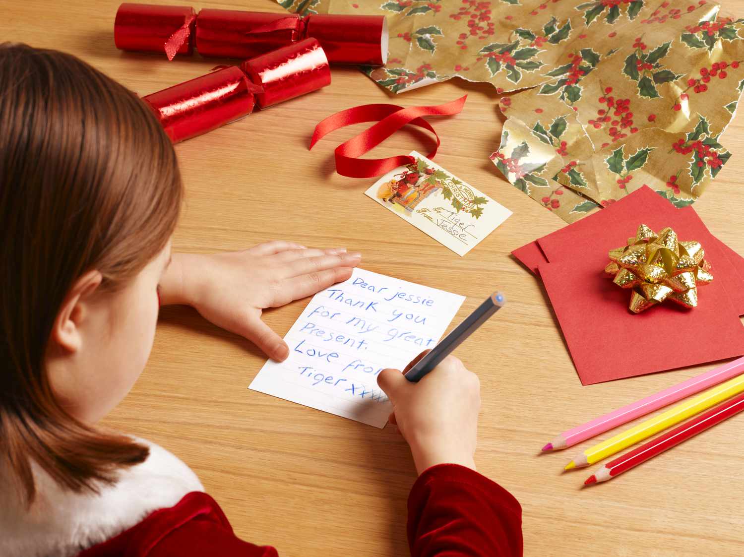 女孩(6 - 7)写圣诞贺卡,在肩上的观点