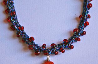 蓝色红色和橙色串珠钩针项链的照片