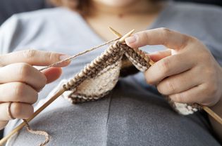 a pregnant woman knitting at home