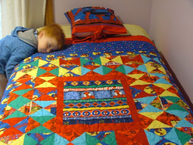 男孩他的头枕在一个蜘蛛侠与匹配的枕头被子。
