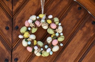 a multicolored egg wreath hanging on a door