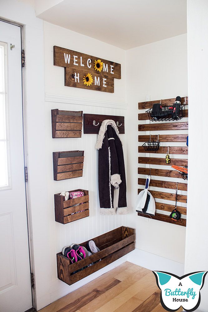 Scrap wood wall organizer hanging on a white wall under a "welcome home" sign