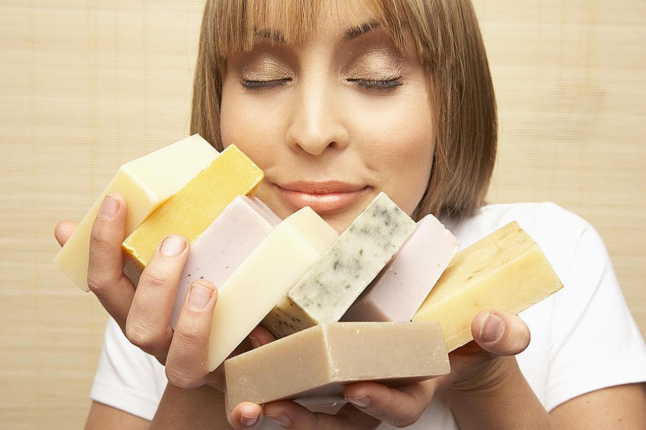 Young woman smelling assorted bars of soap, eyes closed, close-up